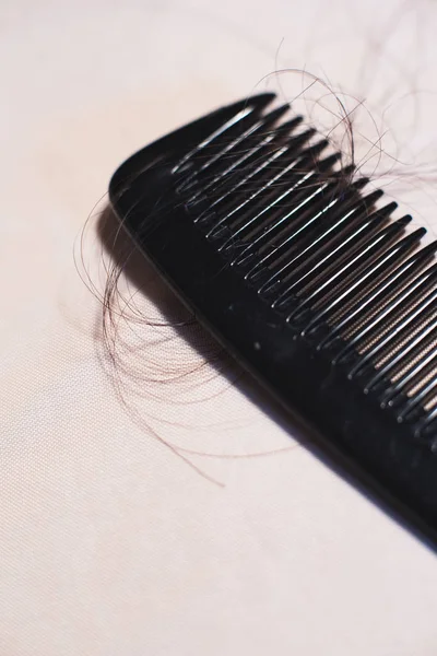 Parlak kumaş üzerinde kahverengi saçlı siyah tarak yakın çekim.