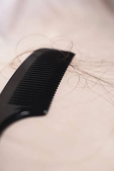 Close-up de pente preto com cabelos castanhos em tecido brilhante . — Fotografia de Stock