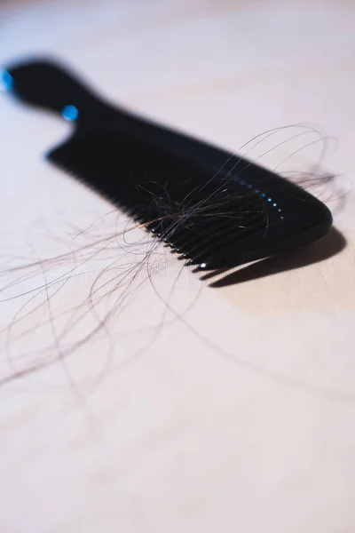 Zbliżenie czarnego grzebienia z brązowymi włosami na jasnym tkaninie. — Zdjęcie stockowe