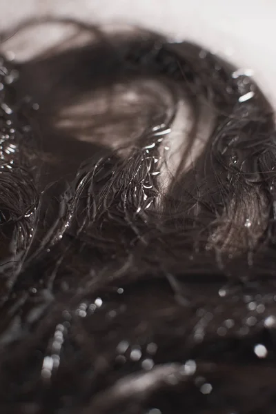 Detalhe do cabelo encaracolado marrom deitado na água na pia . — Fotografia de Stock
