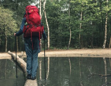 Kırmızı sırt çantasındaki adam düşmüş bagajın üzerinde yürüyor..