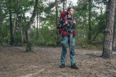 Baharda ormanda kırmızı sırt çantalı genç adam..