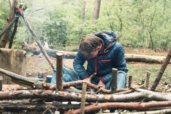 Ung man som förbereder lägereld i skogen. — Stockfoto