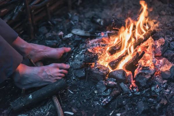 Männliche Füße wärmen sich am Lagerfeuer. — Stockfoto
