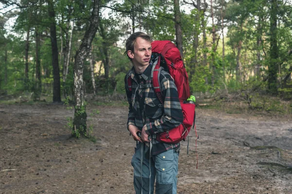 春天，一个背着红色背包在森林里的年轻人. — 图库照片