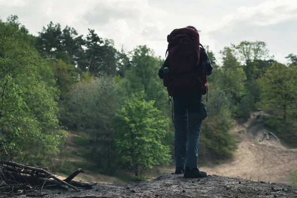Jovem com mochila vermelha na borda do desfiladeiro na floresta de primavera . — Fotografia de Stock