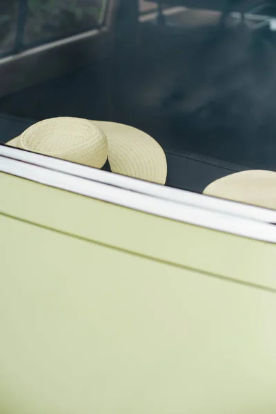 Two straw hats on back seat of vintage car. View through rear wi — Stock Photo, Image