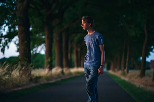 Giovane sulla strada di campagna al tramonto . — Foto Stock