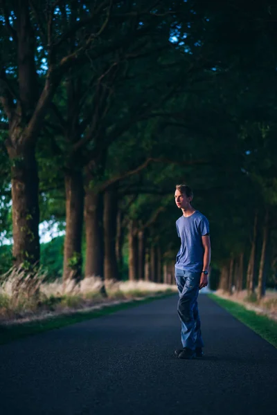 Giovane sulla strada di campagna al tramonto . — Foto Stock