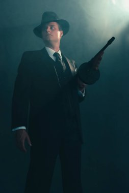 Retro gangster duman makineli tüfek ile duruyor.