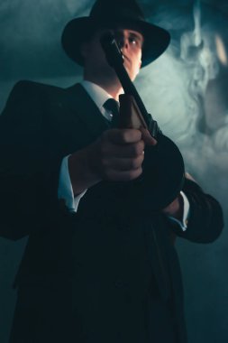 Sisli gece şapkaretro gangster makineli tüfek ile vuruyor.