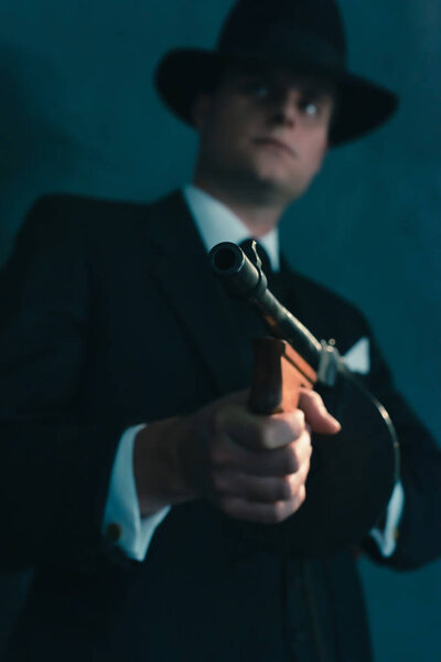 Retro gangster in hat shoots with machine gun.