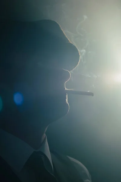 Şapkalı retro adam dumanlı odada sigara içiyor. Yan görünüm. — Stok fotoğraf