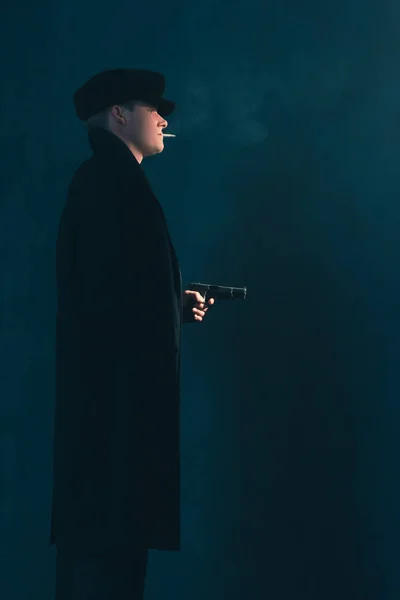 Retro mobster with cigarette shoots with gun. Side view. — Stock Photo, Image