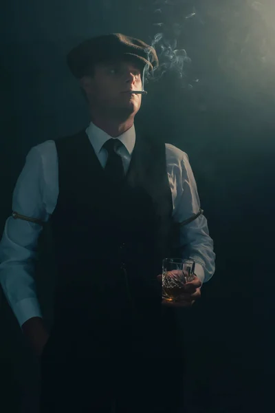 Retro businessman with cap smokes cigarette in smoky room.