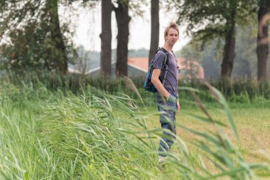 Sırt çantası ile genç adam kırsal sahiptir.
