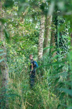 Yaz çalıları arasında genç adam omuz üzerinden bakar.