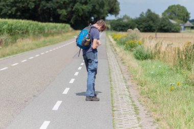 Yaz aylarında ülke yolda sırt çantası ile genç adam.