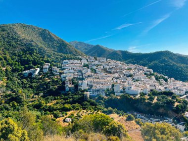Açık mavi gökyüzünün altındaki bir dağın yamacında tipik beyaz Endülüs İspanyol köyü. Ojen, Malaga, İspanya.