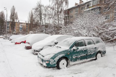 Otoparktaki kar fırtınasında araçlar karla kaplı.