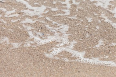 Deniz su dalgaları ile kum plajı kabarcıklar yukarıya kapatmak