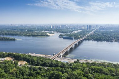 Güneşli bir yaz gününde mavi nehir ve metro köprüsünün havadan görünümü. Kiev, Ukrayna