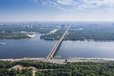 Güneşli bir yaz gününde mavi nehir ve metro köprüsünün havadan görünümü. Kiev, Ukrayna