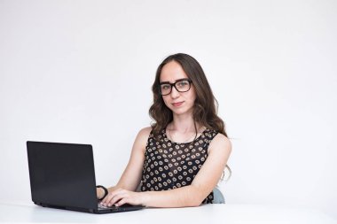 Hastalıklar hakkında söyle. Dizüstü bilgisayar ile beyaz arka plan üzerinde güzel esmer Yöneticisi kız portresi. O şu kamera gülümseyen önünde oturur ve ciddi görünüyor