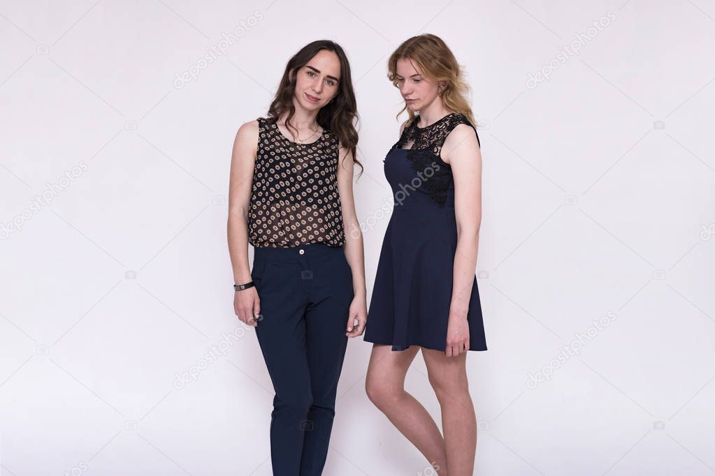 portrait of two beautiful brunette girls and blondes on a white background showing different emotions in different poses. They stand right in front of the camera and look happy