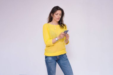 Telefonu olmadan bir şey yapamam. Bir akıllı telefon elinde yazarak beyaz zemin üzerine güzel bir esmer kız portresi. O şu kamera gülümseyen önünde duran ve mutlu görünüyordu