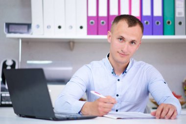 Gerçekten dikkatle dinliyorum. Office bir dizüstü bilgisayar ile bir genç erkek Müdürü portresi. O kamera önünde oturur ve ciddi görünüyor.