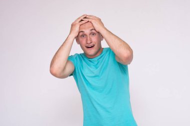 farklı pozlar farklı duygular gösterilen beyaz bir arka plan üzerinde bir T-shirt yakışıklı bir genç adam portresi. O doğrudan kamera önünde duruyor ve kameraya bakar