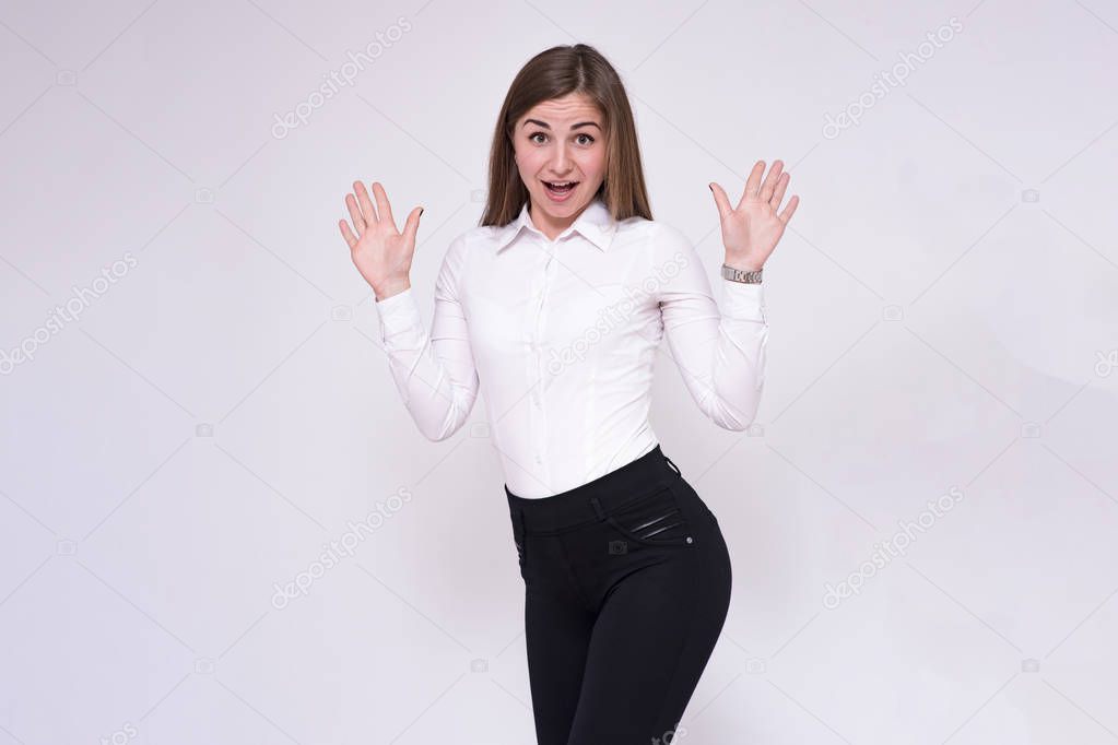 portrait of a beautiful brunette girl on a white background in a white shirt with different emotions in different poses. She is standing right in front of the camera smiling and looking happy