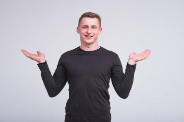 Farklı pozlar bir ürün gösterilen beyaz bir arka plan üzerinde hoş bir genç adam portresi. Doğrudan kamera ve gülümsüyor önünde durduğunu
