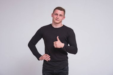 Beyaz arka plan üzerinde ok gösterilen hoş bir genç adam portresi. Şu kamera gülümseyen önünde duruyor ve mutlu görünüyor