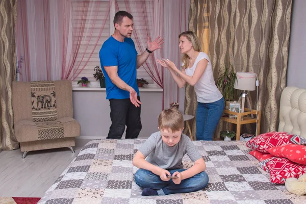 portrait of husband and wife and son aged 6 years in the room: family difficulties, problems, family relationships. They sit in front of the camera to quarrel and look unhappy