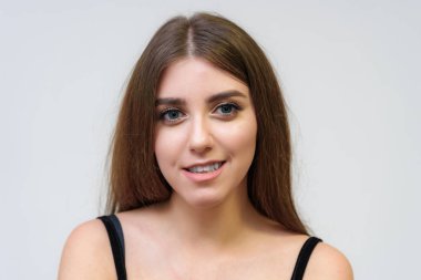 Stüdyo bir gülümseyen mutlu güzel esmer kız beyaz arka plan üzerinde portresi. Doğrudan çeşitli teşkil etmektedir kamera önünde duruyor.