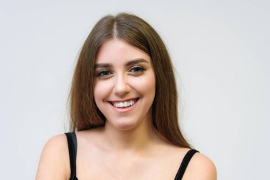 Stüdyo bir gülümseyen mutlu güzel esmer kız beyaz arka plan üzerinde portresi. Doğrudan çeşitli teşkil etmektedir kamera önünde duruyor.