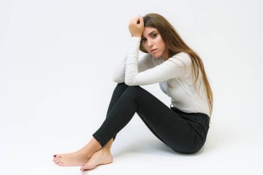 Stüdyo bir gülümseyen mutlu güzel esmer kız konuşuyor ve katta oturan beyaz bir arka plan üzerinde portresi. Çeşitli teşkil etmektedir kamera önünde doğru söylüyor.