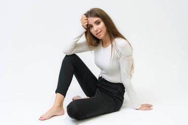 Stüdyo bir gülümseyen mutlu güzel esmer kız konuşuyor ve katta oturan beyaz bir arka plan üzerinde portresi. Çeşitli teşkil etmektedir kamera önünde doğru söylüyor.