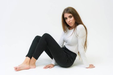 Stüdyo bir gülümseyen mutlu güzel esmer kız konuşuyor ve katta oturan beyaz bir arka plan üzerinde portresi. Çeşitli teşkil etmektedir kamera önünde doğru söylüyor.