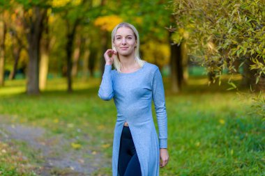 Güzel sarışın kız parkta sonbahar günbatımı güneş akşam sokakta fotoğraf portre. Gülümseyen ve mutlu görünüyordu kamera önünde duruyor.
