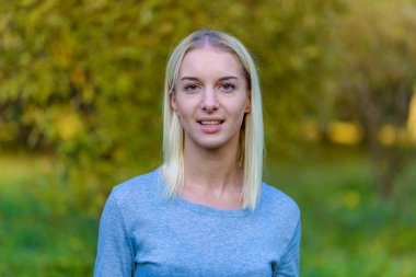 Güzel sarışın kız parkta sonbahar günbatımı güneş akşam sokakta fotoğraf portre. Gülümseyen ve mutlu görünüyordu kamera önünde duruyor.