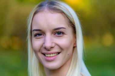 Güzel sarışın kız parkta sonbahar günbatımı güneş akşam sokakta fotoğraf portre. Gülümseyen ve mutlu görünüyordu kamera önünde duruyor.