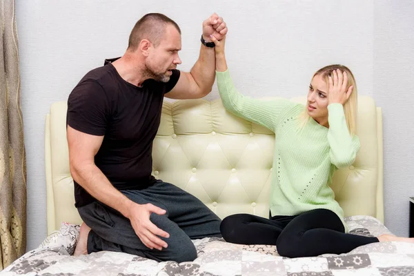photo snapshot of family problems, family relationships dissatisfied men and women, husband and young wife in a room on the sofa. They are sitting right in front of the camera, looking upset.