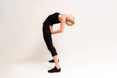 Studio fotoğraf güzel bir sarışın kızın germe egzersizleri beyaz bir arka plan üzerinde fitness yapıyor. Gülümseyen ve mutlu görünüyordu kamera önünde doğru söylüyor.