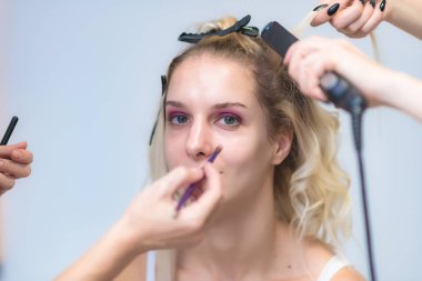 İş bir profesyonel makyaj sanatçısı - güzellik uzmanı, gölgeler modelinin göze güzel bir sarışınla yüzünde bir fırçayla makyaj yapar. Kaş boyama.