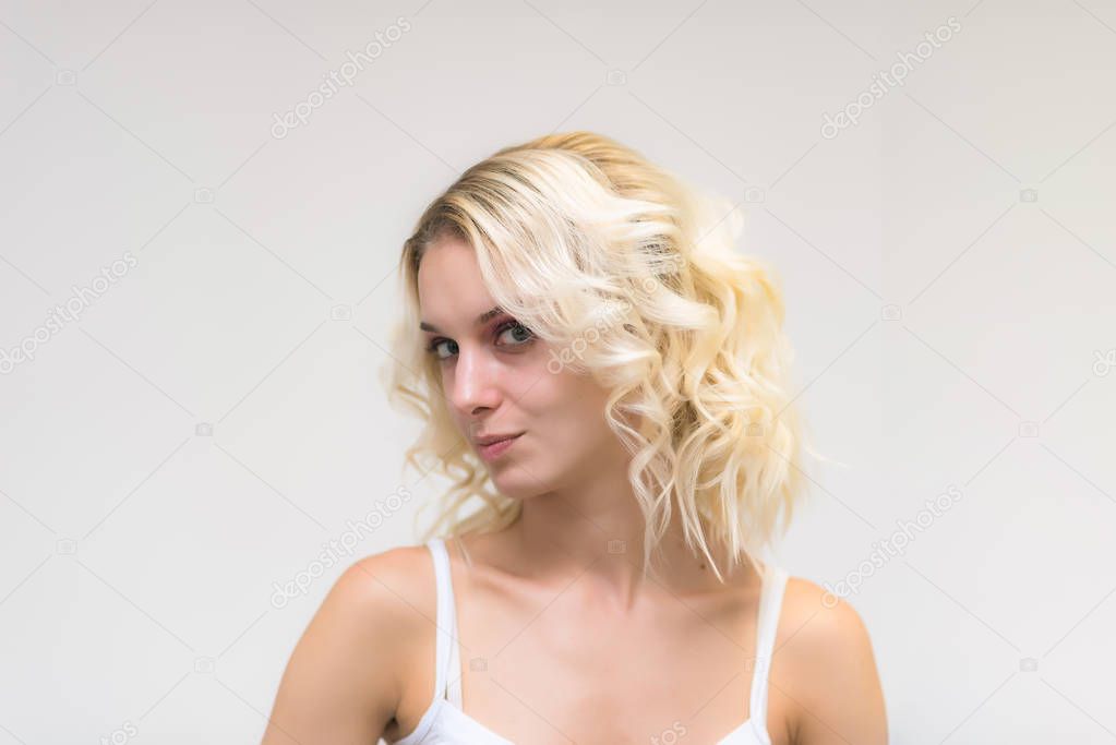 Portrait of a beautiful blonde girl while working as a professional beautician make-up artist. She sits right in front of the camera and looks happy.