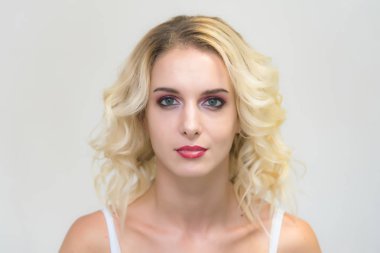 Güzel sarışın kız mükemmel makyaj ile beyaz bir arka plan üzerinde güzellik portresi. Güzellik stili modeli kamera önünde haklı ve mutlu görünüyor.