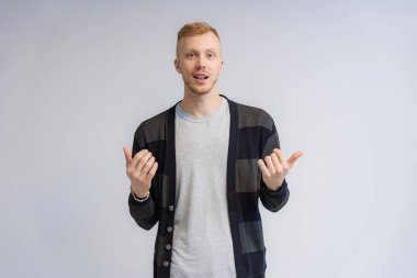 Beyaz arka planda konuşan gülümseyen bir gencin stüdyo portresi. Farklı pozlarda, farklı duygularla kameranın önünde duruyor..